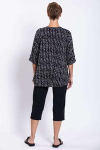 Back view of a woman wearing a black and white abstract print blouse with 3/4 sleeves