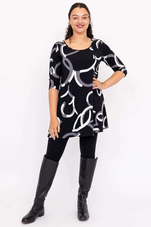 Full-body front view of model in black A-line dress with 3/4 sleeves and monochrome pattern