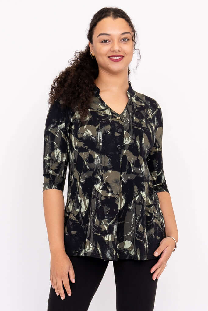 Woman wearing a black and green abstract print V-neck pullover top with 3/4 sleeves