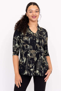 Woman wearing a black and green abstract print V-neck pullover top with 3/4 sleeves