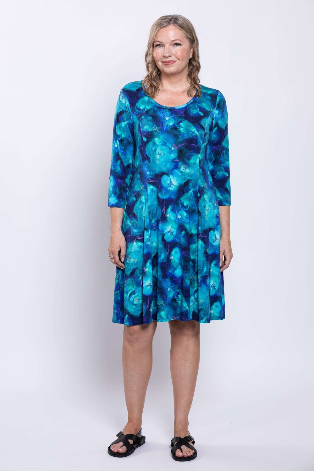 Model showing Callie dress, relaxed pose, vibrant blue print and 3/4 sleeves