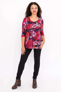 Full body view of woman in red floral 3/4 sleeve bamboo top and black pants
