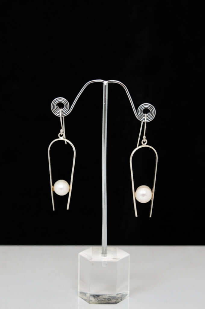 Pair of 925 sterling silver drop earrings with pearl accents on a display stand