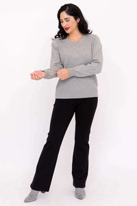 Woman adjusting ribbed cuff on grey cable knit sweater