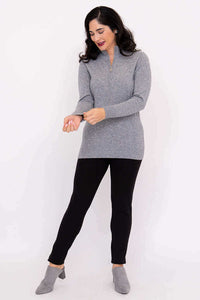 Woman adjusting sleeve of grey cashmere wool half-zip sweater with black pants
