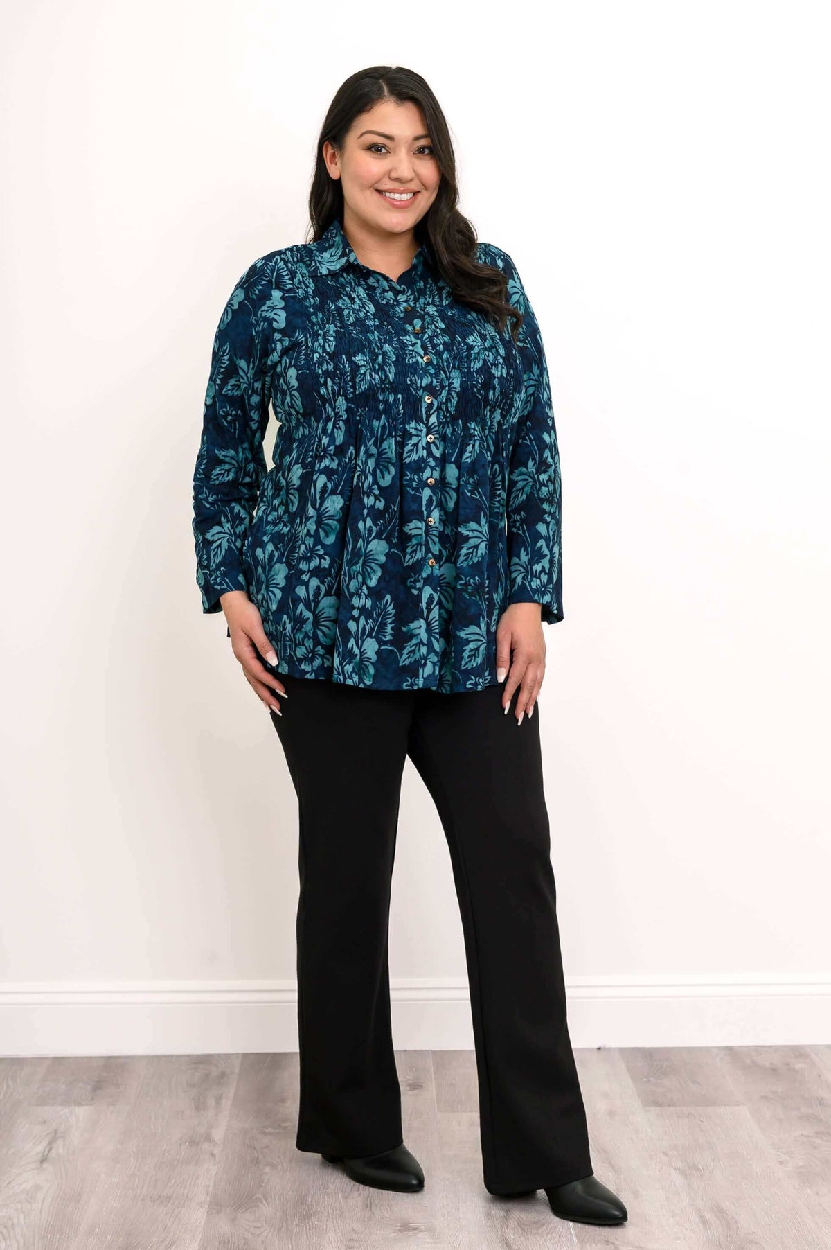 Model angled in blue floral smocked shirt and black pants