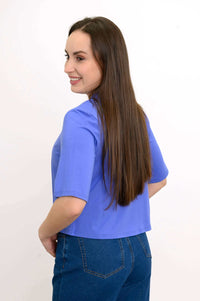 Back angled view of woman in a blue cropped short sleeve bamboo jacket showing drape and fit