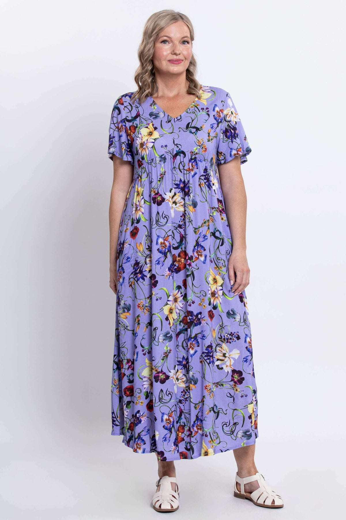 Angled front view of woman in flowing violet floral empire waist dress
