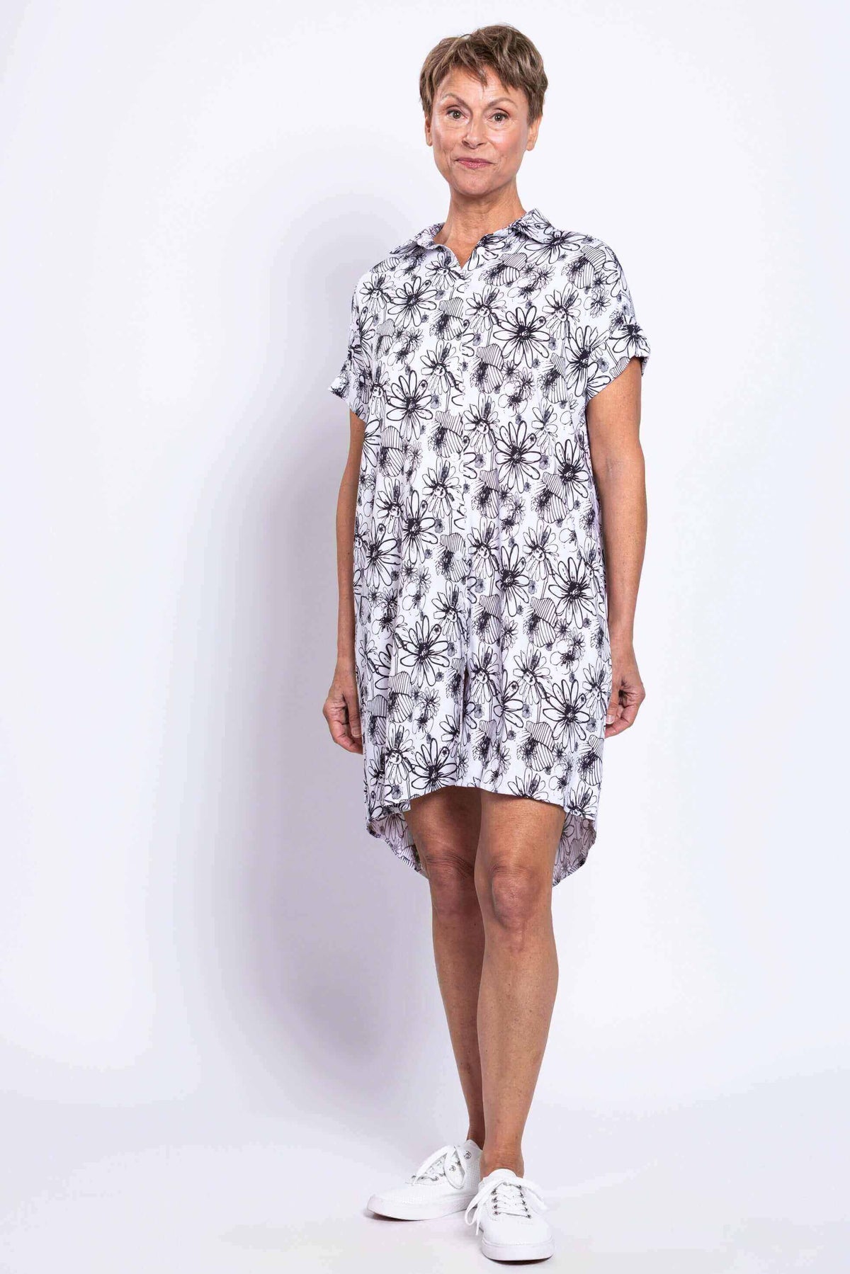 Front angled view of a woman modeling a black and white floral shirt dress