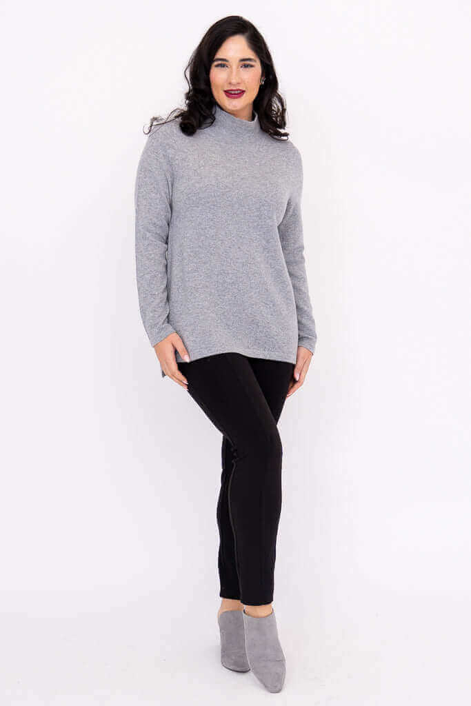 Angled front view of model showcasing grey mock neck sweater and black pants