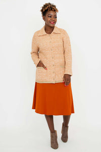 Model angled left, hands in pockets, in Chanel Cardigan and orange dress