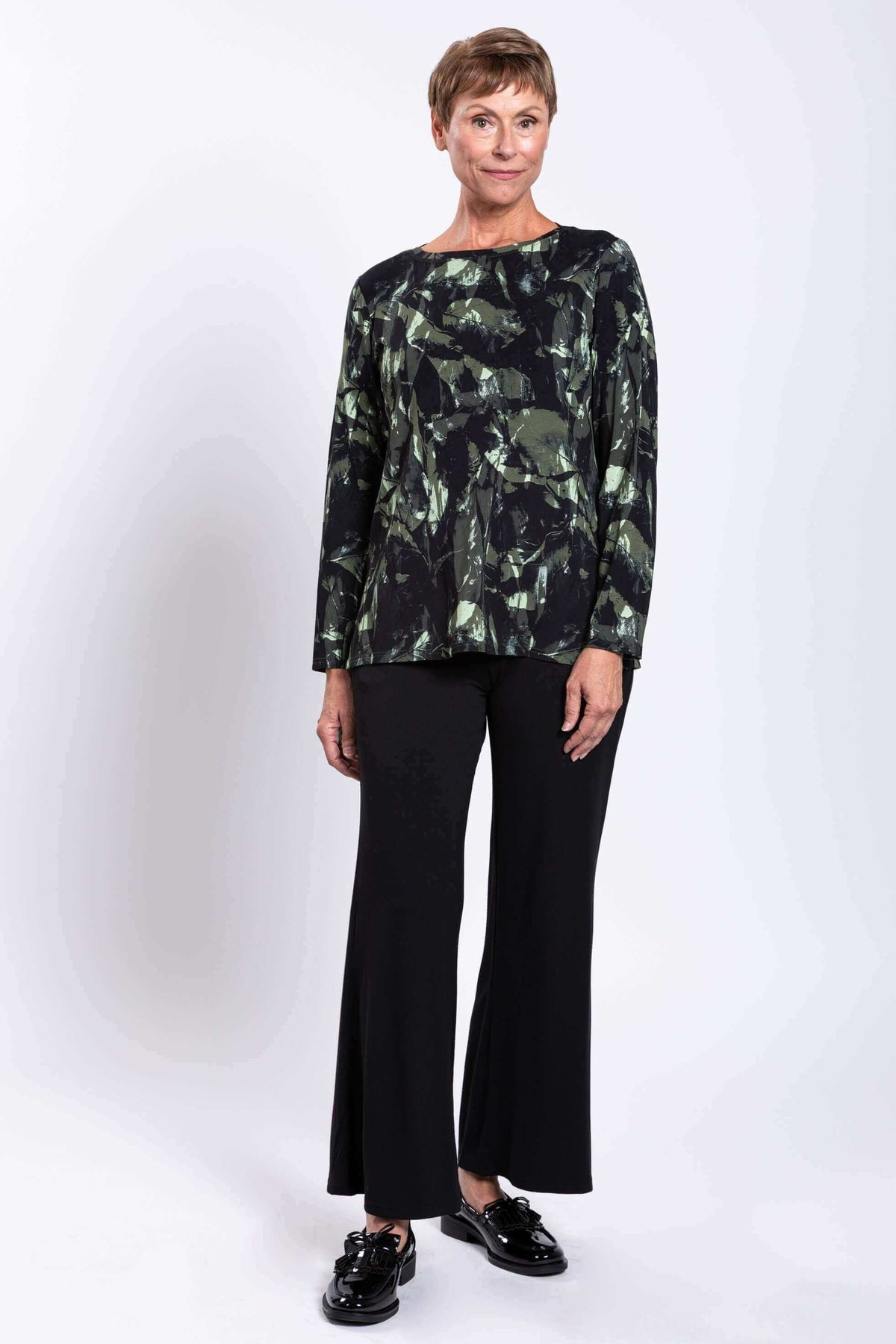 Slight angle front view of woman modeling a longline top with forest abstract print