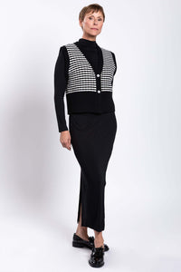 Angled front view of a woman in a striped wool-cashmere vest and black outfit