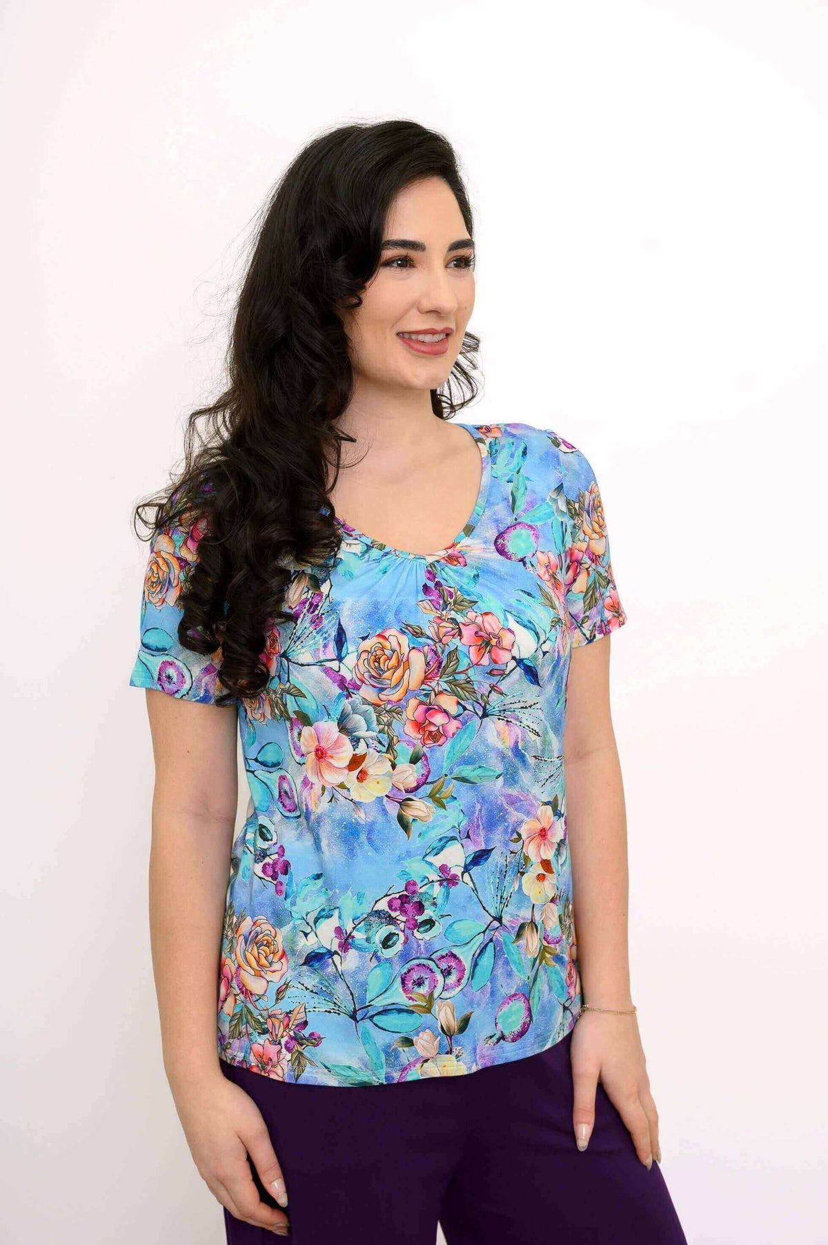 Woman in blue floral short sleeve bamboo top, angled pose with relaxed smile