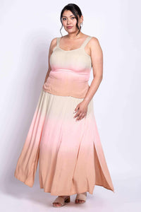 Angled front view of model in peach and pink dip-dye maxi skirt showing side slits