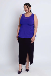 Angled front view of model in purple mesh tank top and long black skirt