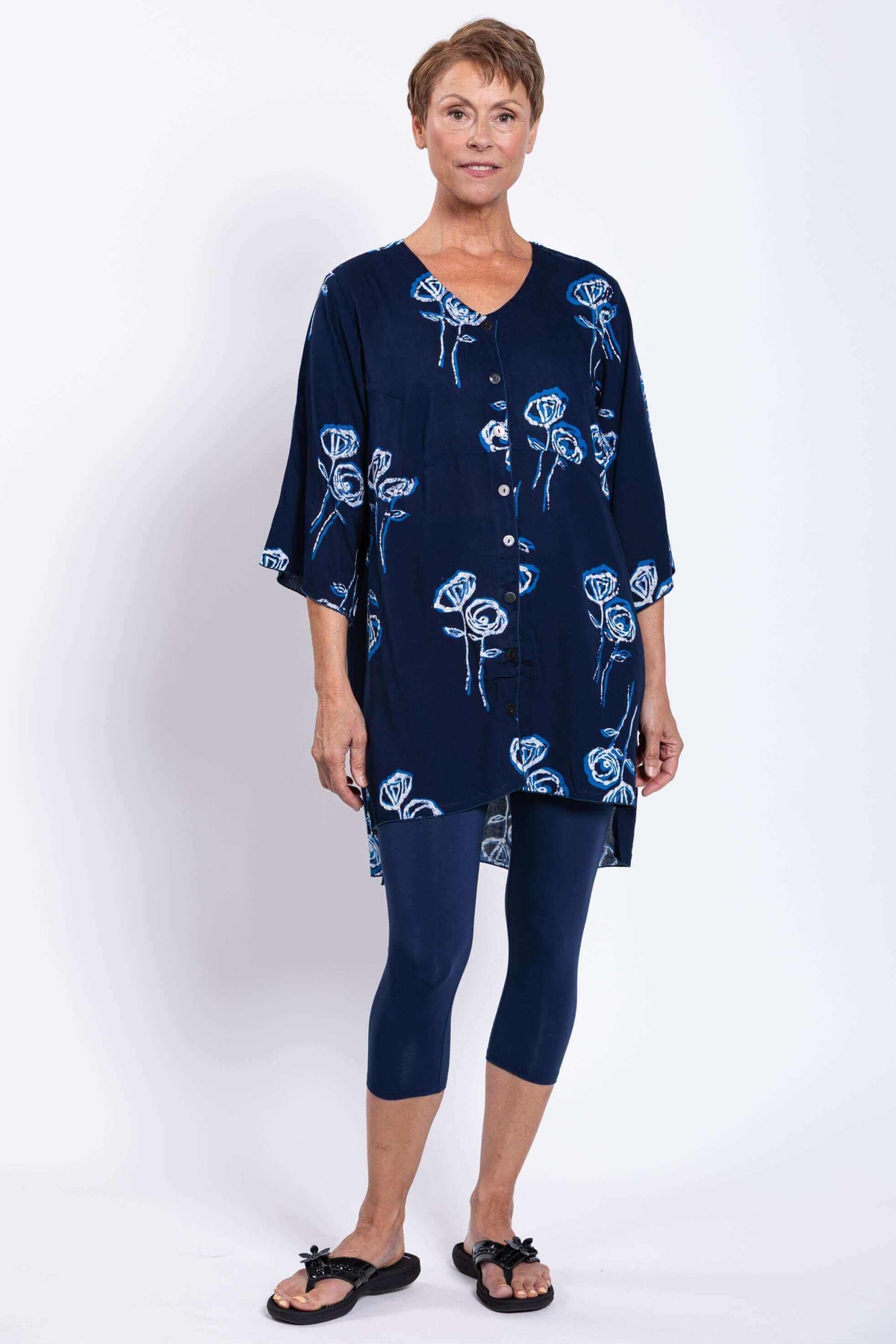 Angled front view of woman in navy floral Darla blouse with button front and high-low hem