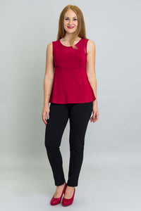 Woman standing in red tank top and black pants, angled front view