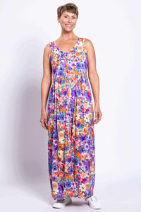 Slightly angled front view of woman in a sleeveless vibrant floral maxi dress, hands relaxed
