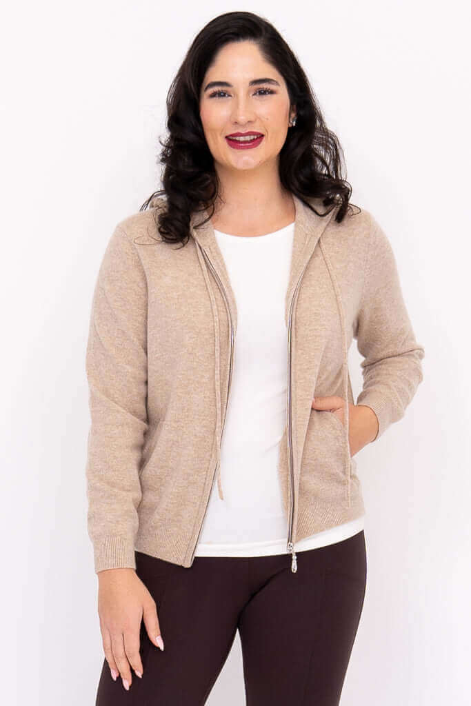 Woman in beige hoodie with one hand in pocket, front angled view