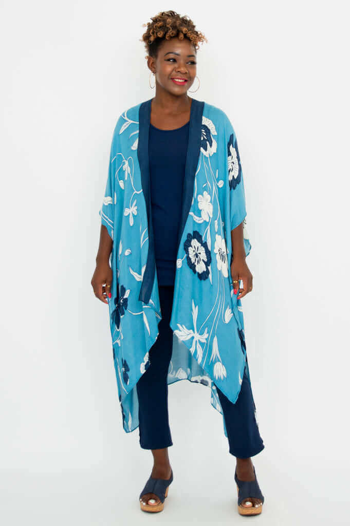 Angled front view of woman in blue floral kimono wrap and navy pants