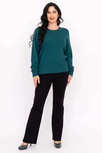 Woman in a teal cable knit sweater with black pants and teal shoes, angled front view