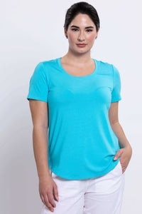 Front angled view of woman with hand in pocket wearing turquoise bamboo tee