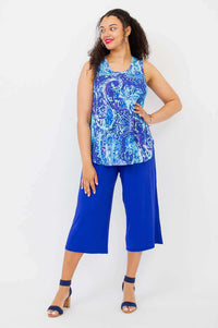 Woman posing in a blue batik print tank top and blue pants, angled stance