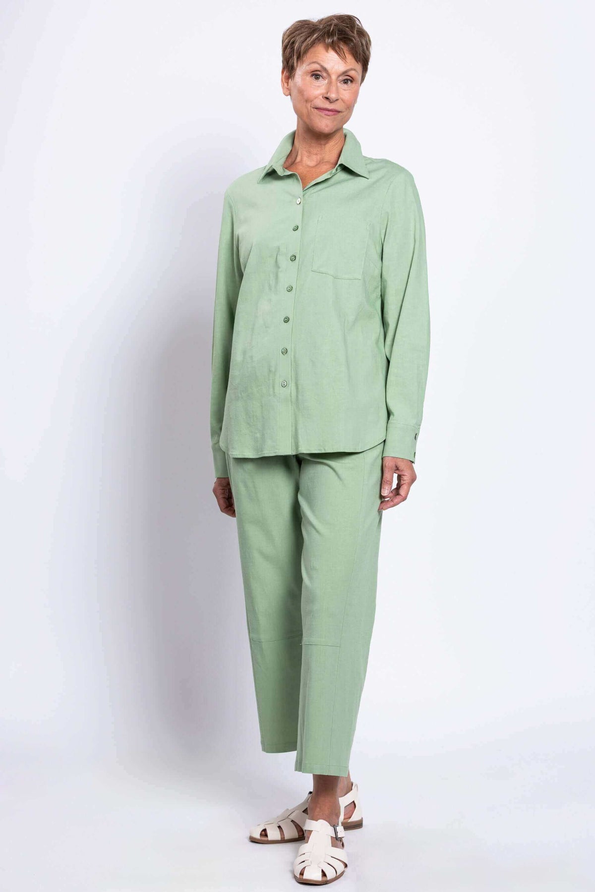 Woman in light green shirt and pants, angled pose with hands by side