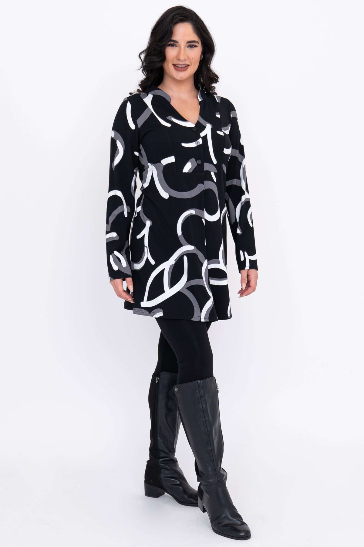 Angled view of tunic with bold abstract print, worn over leggings and boots.