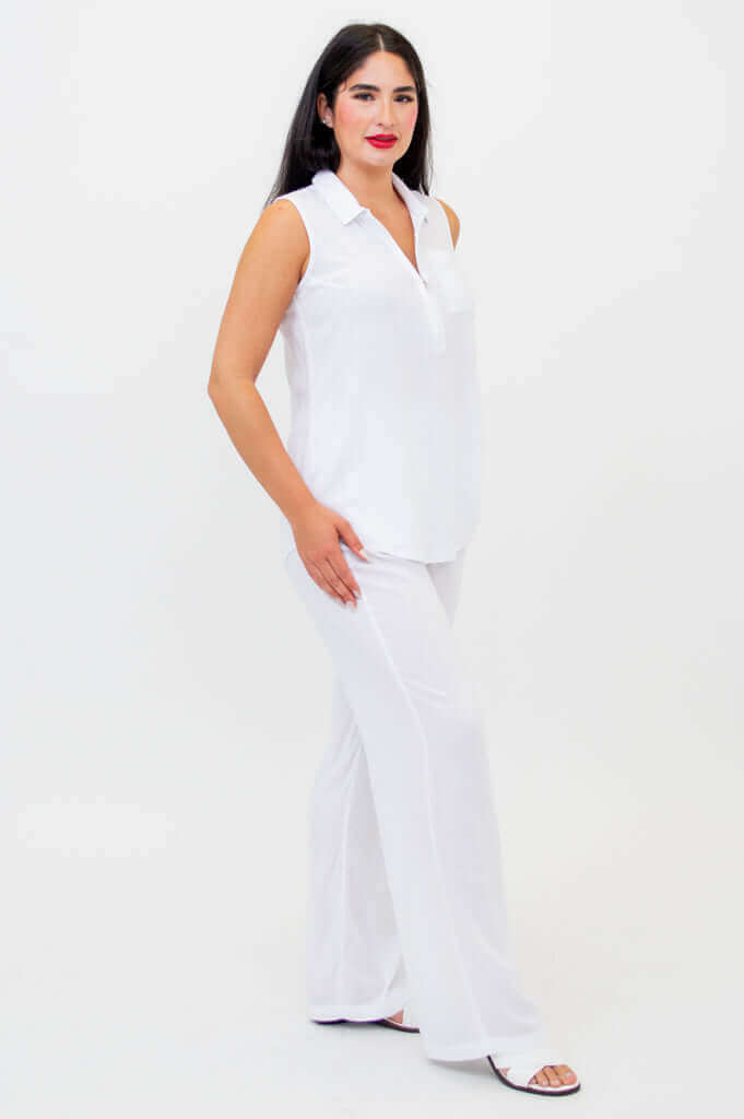 Angled side view of woman dressed in a sleeveless white tank top and wide-leg pants