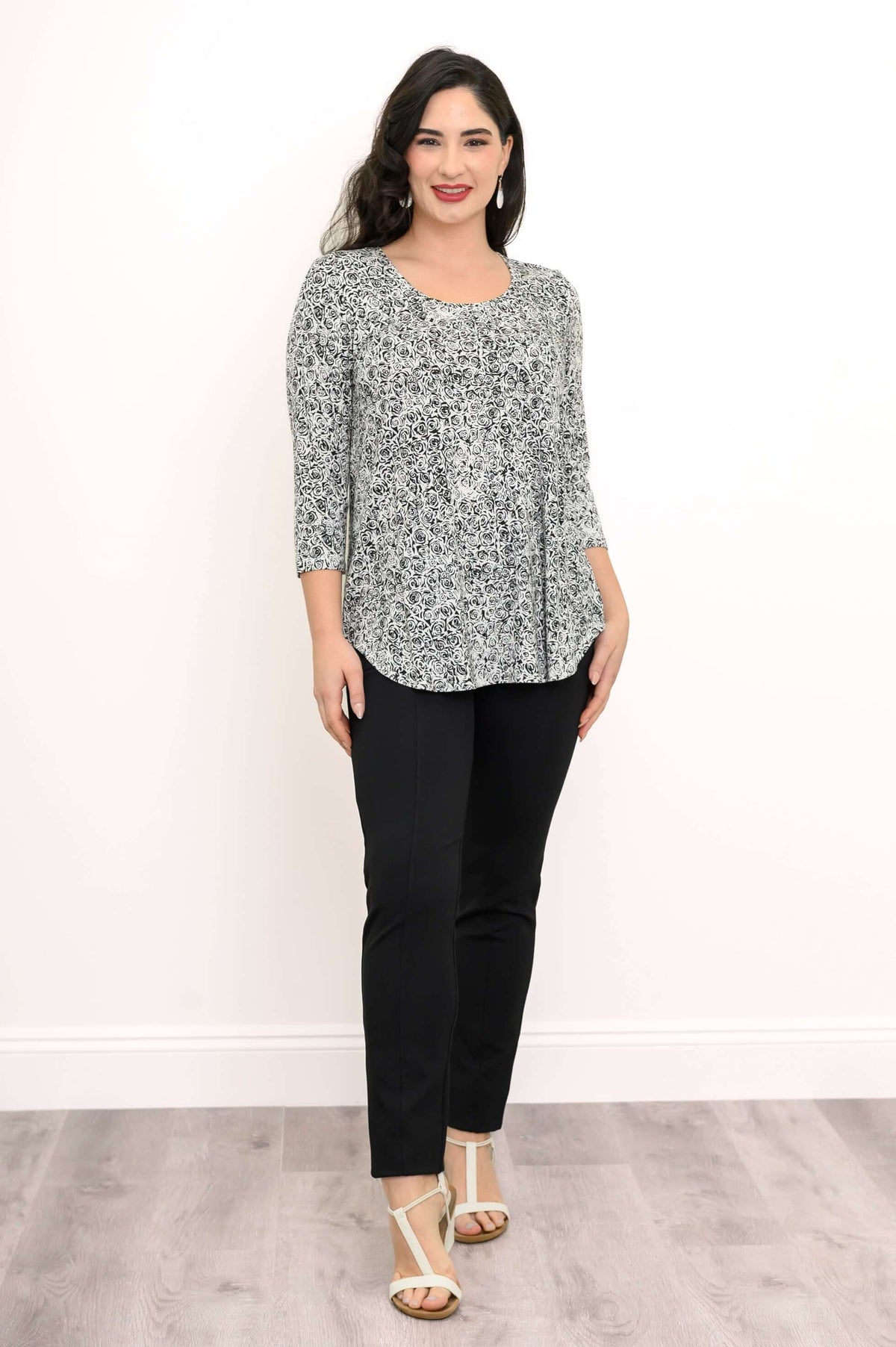 Angled standing view of woman in floral print bamboo top and black pants