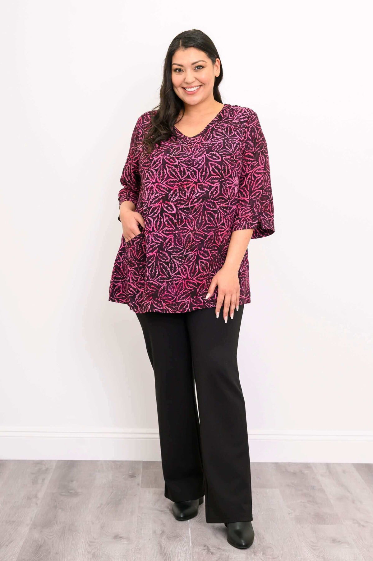 Woman wearing Evelyn Top in pink leaf pattern with one hand in pocket, angled stance