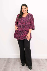 Woman wearing Evelyn Top in pink leaf pattern with one hand in pocket, angled stance