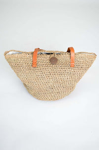 Angled view of the Namaste rattan tote bag with button closure and leather handles