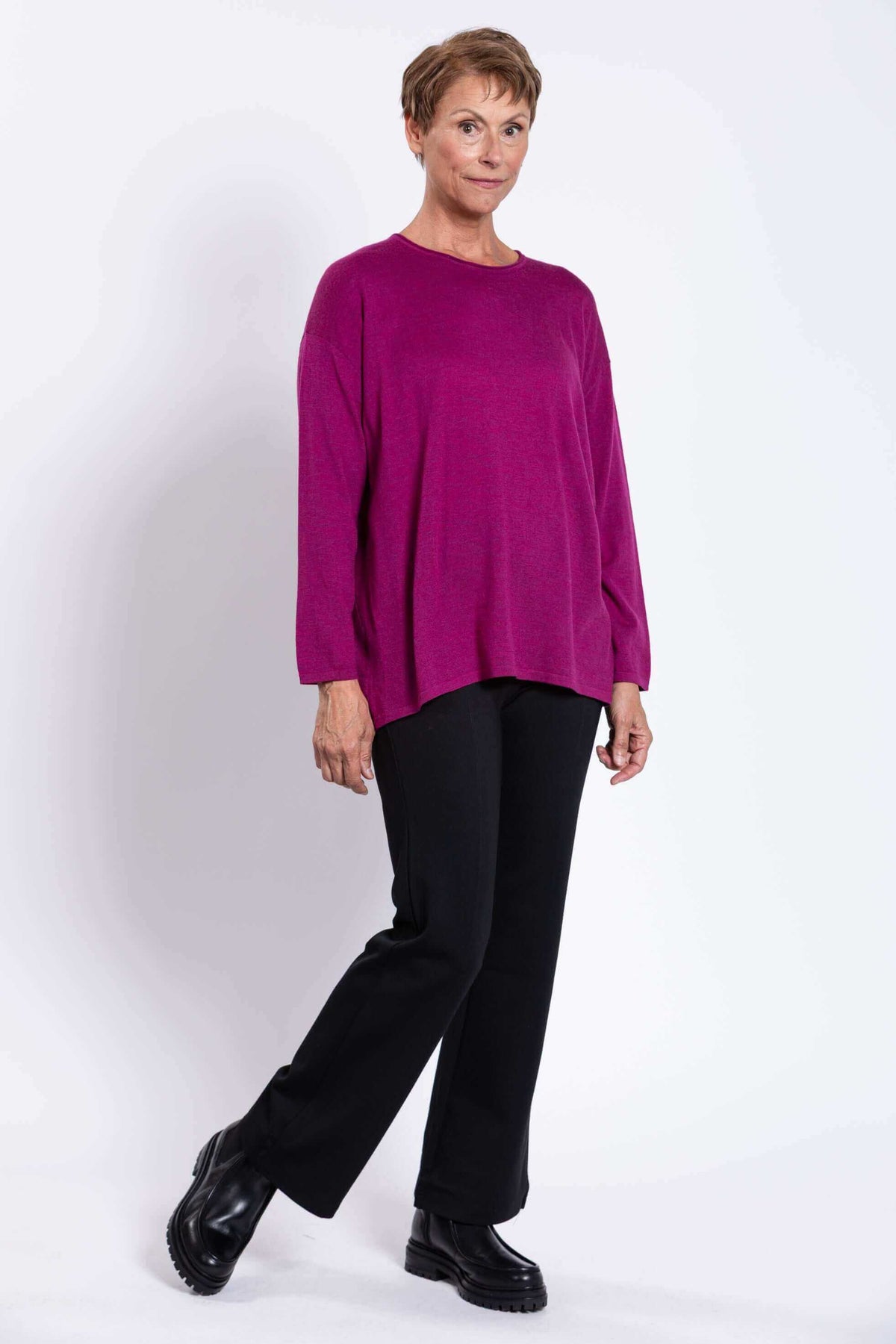 Side angled view of a woman showcasing a berry color Merino wool sweater outfit