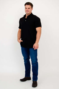 Man wearing black bamboo polo shirt with blue jeans standing at an angle
