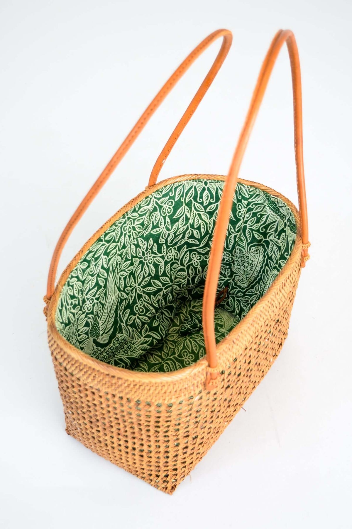 Angled view of rattan picnic basket with green printed fabric interior