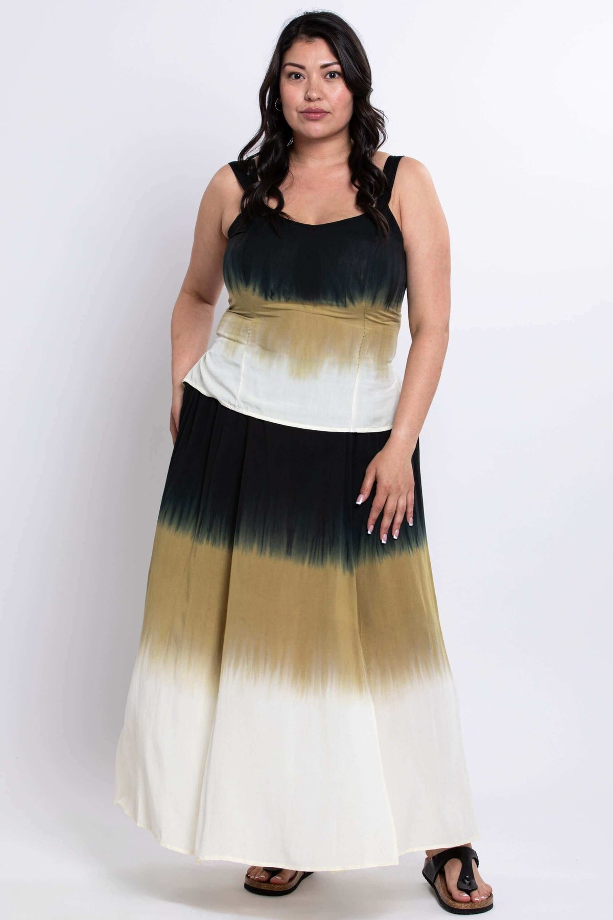 Woman in a tie-dye maxi skirt, standing relaxed with hand in pocket, front angled view