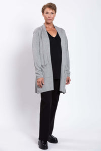 Woman in a grey open cardigan, angled view with hands at sides, over a black outfit