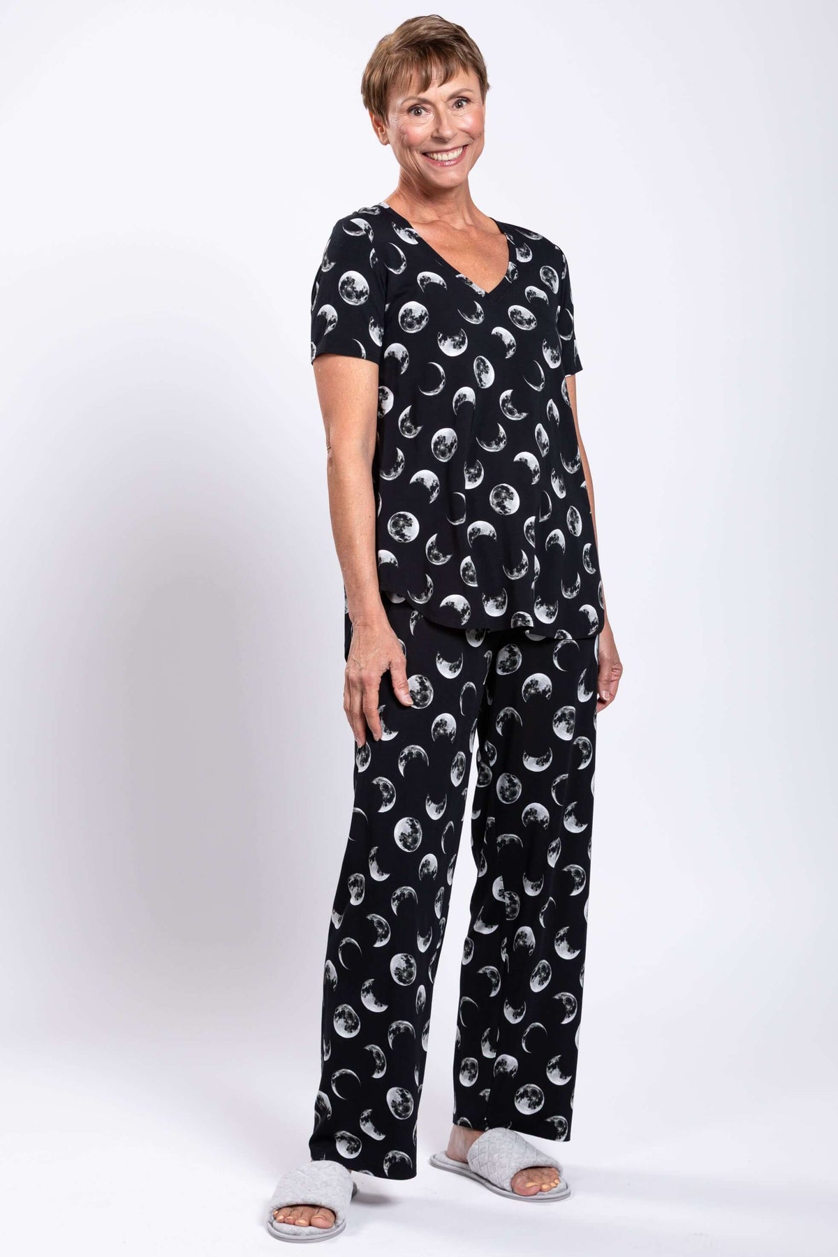 Woman smiling in black moon phase V-neck top and pants, angled view