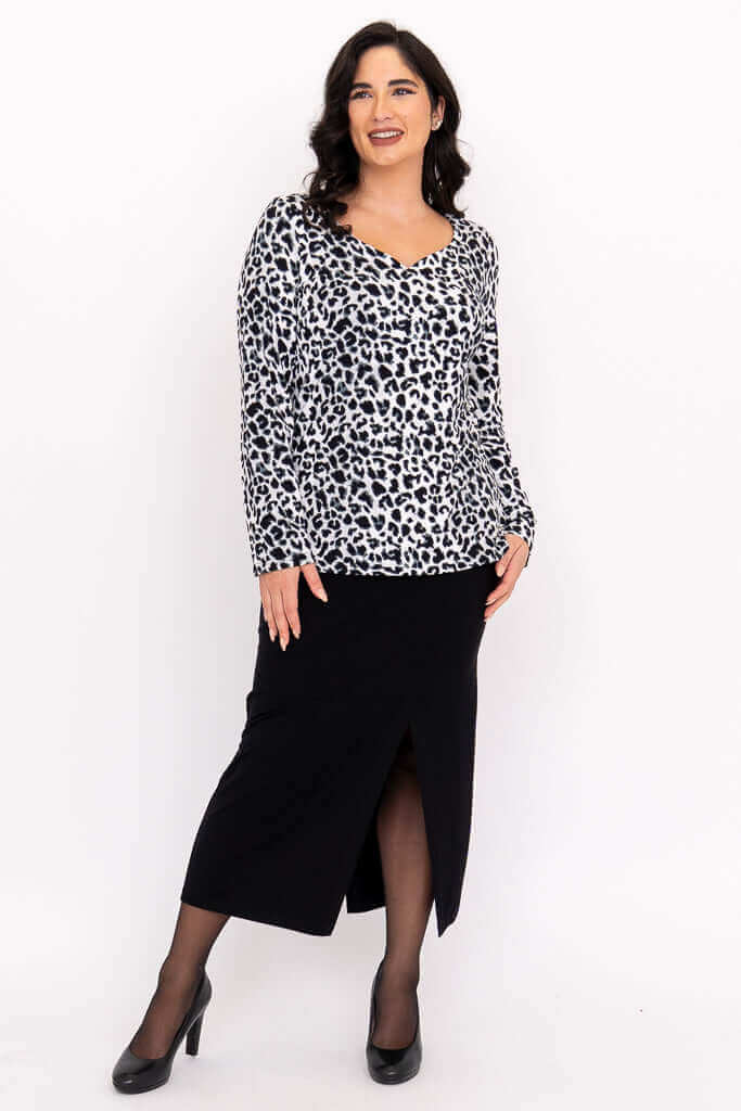 Model posing in Annette wild print top and black skirt, angled view