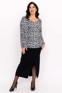 Model posing in Annette wild print top and black skirt, angled view