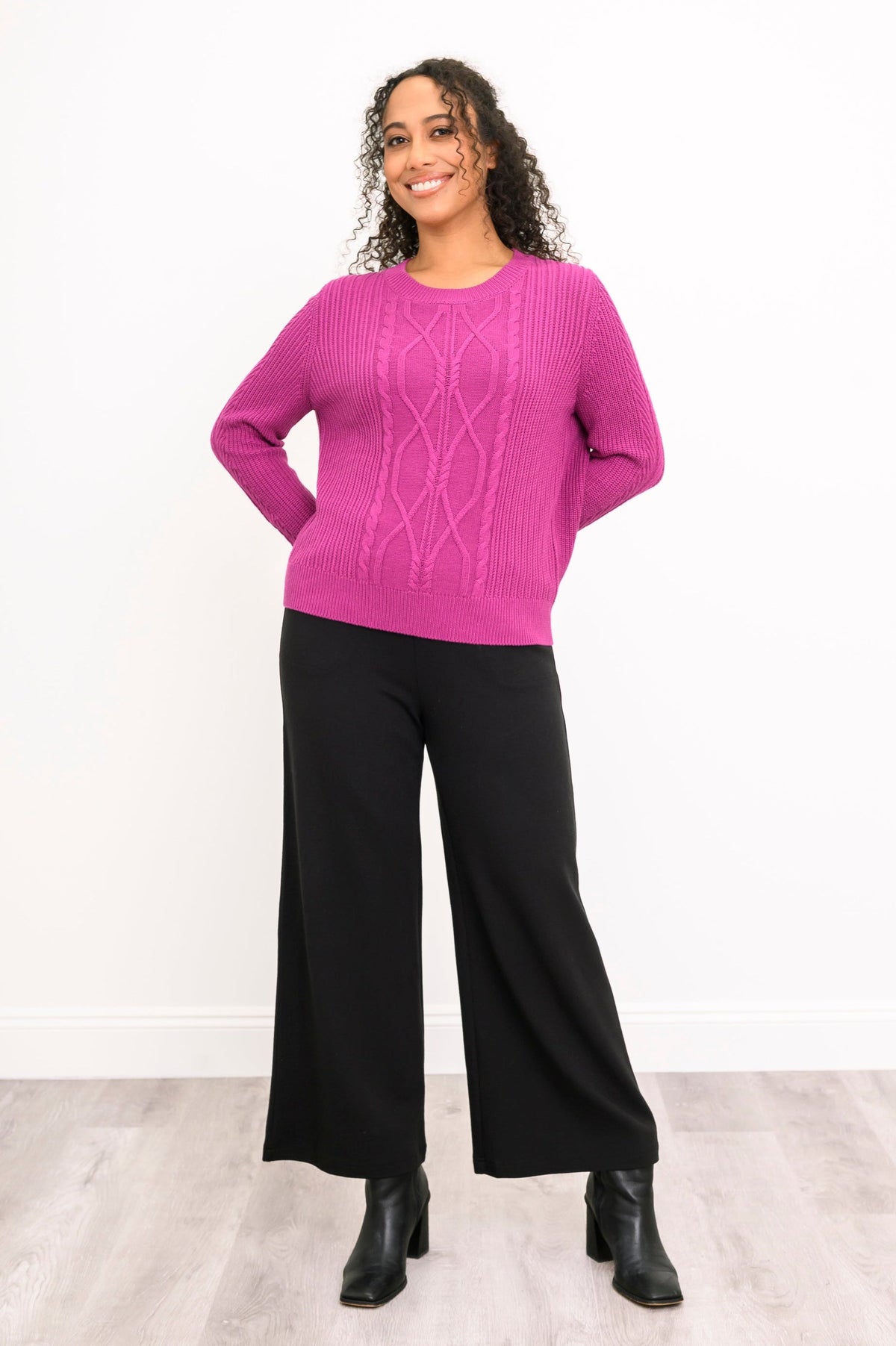 Front view of a vibrant rose-pink knit top and black trousers, highlighting a comfortable and relaxed drape.