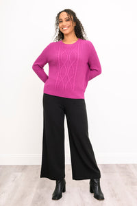 Front view of a vibrant rose-pink knit top and black trousers, highlighting a comfortable and relaxed drape.
