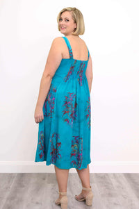 Back view of a woman in a sleeveless aqua blue midi dress with elasticized back