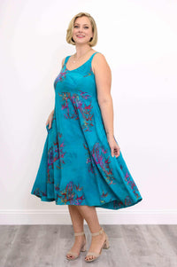 Woman wearing a flowy aqua blue sleeveless midi dress with purple floral accents