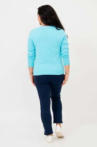 Back view of woman wearing aqua blue button-up cardigan and navy pants