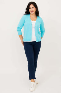 Full body view of woman in aqua blue cardigan, white top, and navy pants