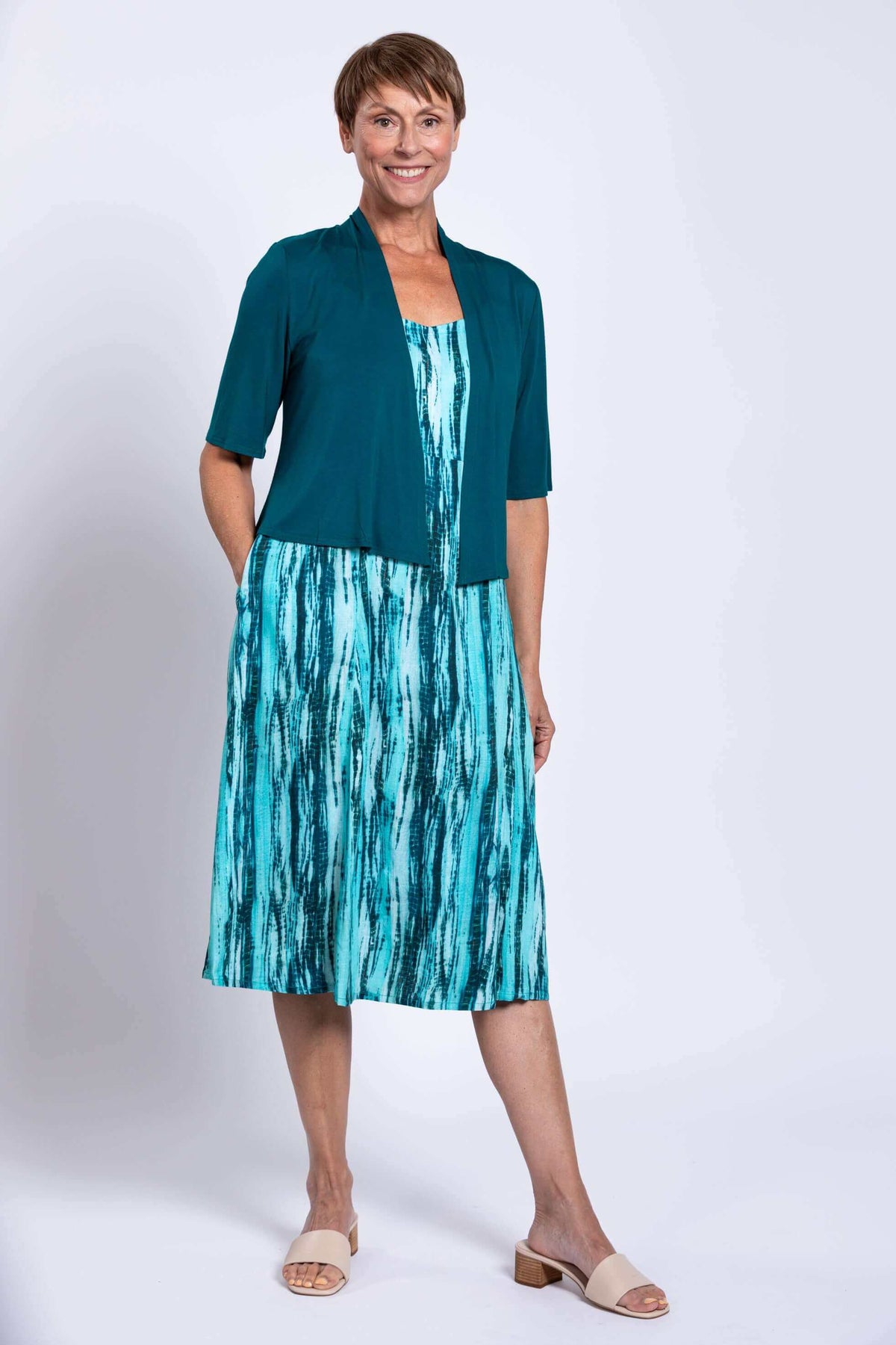 Woman in aqua streak dress styled with a teal shrug, showcasing versatile outfit